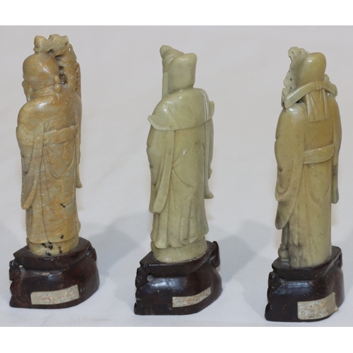 690 - 3 Oriental soapstone figures of standing gentlemen holding staffs etc., on pierced bases, 15cm high