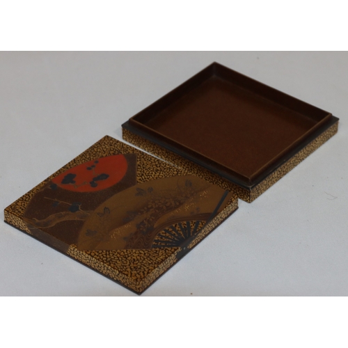 721 - A signed Oriental lacquered square box on gilt ground with fan, floral and leaf decoration, with cov... 