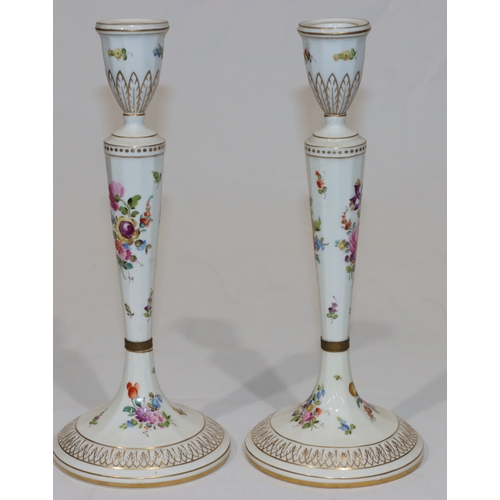 76 - A pair of Continental porcelain candlesticks on turned stems with round sweeping bases, on white gro... 