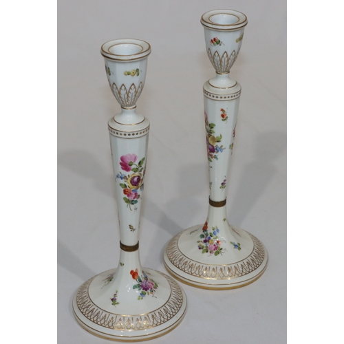 76 - A pair of Continental porcelain candlesticks on turned stems with round sweeping bases, on white gro... 