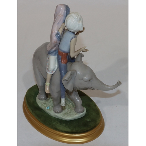 90 - A Lladro group of 2 Eastern figures seated upon elephant with oval gilt base, 23cm high without base