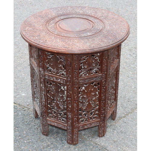 921 - An Eastern round hardwood coffee table with folding stand and allover carved and inlaid brass floral... 