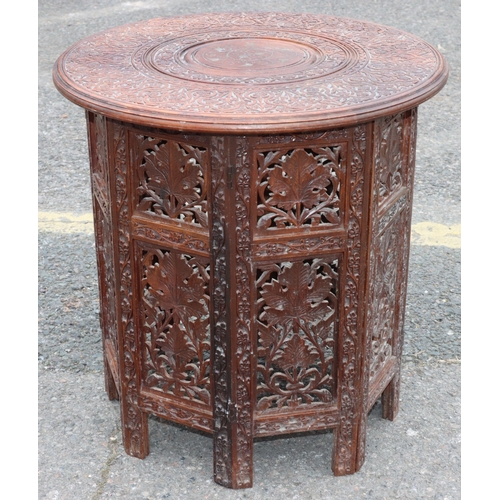 921 - An Eastern round hardwood coffee table with folding stand and allover carved and inlaid brass floral... 