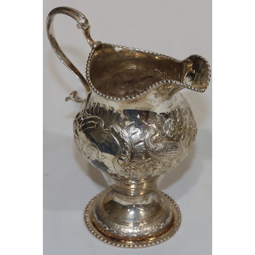 200 - An early George III silver round bulbous shaped milk jug with ball rim and allover embossed bird, fl... 