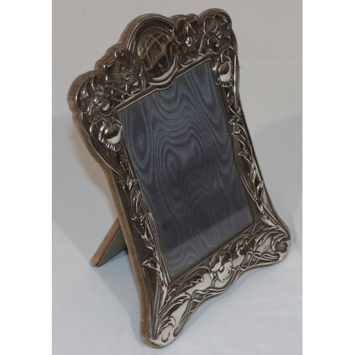 245 - A silver plated freestanding photograph frame with embossed floral, leaf and scroll decoration, 22.5... 