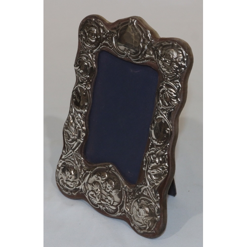 248 - A London silver freestanding photograph frame with embossed, cupid, floral, leaf and scroll decorati... 