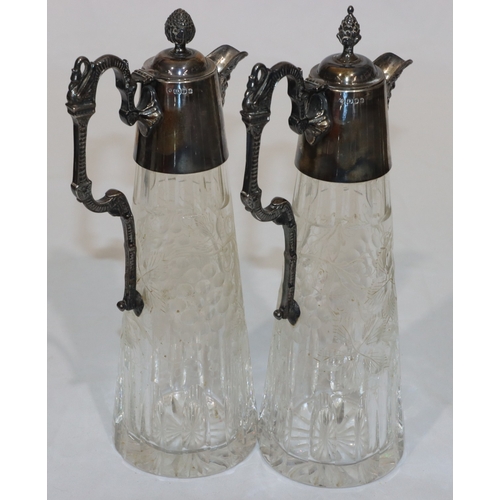 257 - A pair of modern cut glass claret jugs with silver necks, hinged lids, scroll handles and mask head ... 