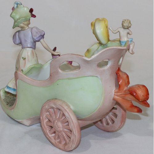 34 - A Continental china jardiniere in the form of a shoe on wheels with raised figure and cupid motif, a... 