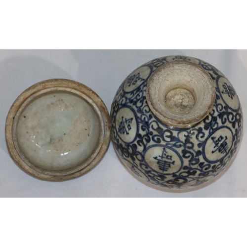 47 - An Oriental round bulbous lidded pot on blue and white ground with allover scroll and inscription de... 