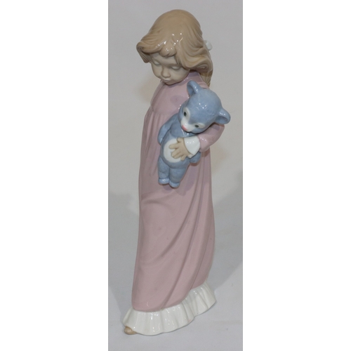 66 - A Nao figure of a young standing girl in pink nightdress holding a teddy bear, 31.5cm high