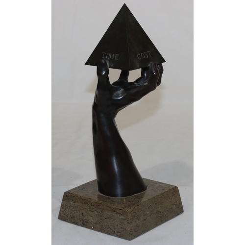 686 - A bronze sculpture of a hand holding a pyramid, marked 