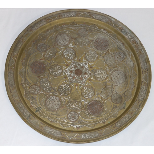 688 - An Eastern brass circular tray with raised inlaid silvered and copper inscription, floral and scroll... 