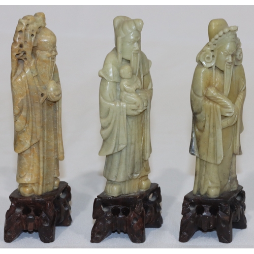 690 - 3 Oriental soapstone figures of standing gentlemen holding staffs etc., on pierced bases, 15cm high