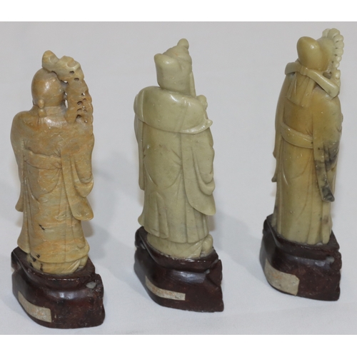 690 - 3 Oriental soapstone figures of standing gentlemen holding staffs etc., on pierced bases, 15cm high