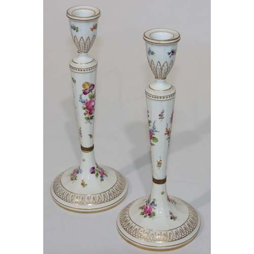 76 - A pair of Continental porcelain candlesticks on turned stems with round sweeping bases, on white gro... 