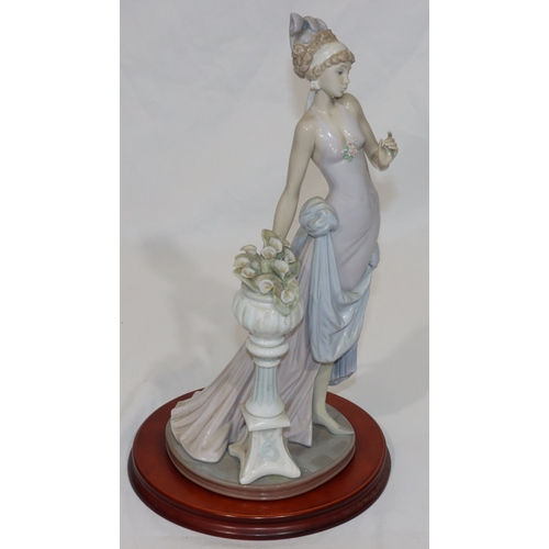 91 - A Lladro figure of a 1920's standing lady, on wooden base, 37cm high without base