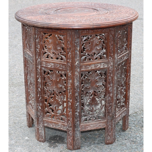 921 - An Eastern round hardwood coffee table with folding stand and allover carved and inlaid brass floral... 