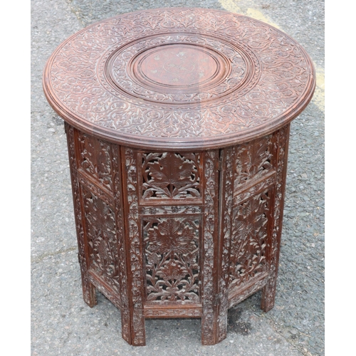 921 - An Eastern round hardwood coffee table with folding stand and allover carved and inlaid brass floral... 