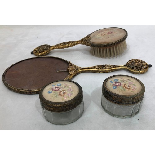 6042 - A part gilt metal dressing table set with embroidered detail, mirror, brush and 2 glass lidded pots ... 