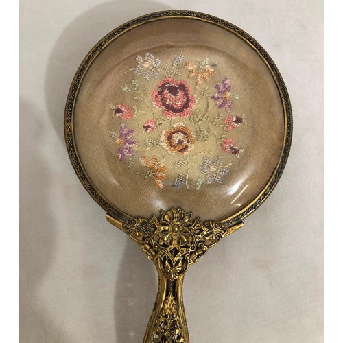 6042 - A part gilt metal dressing table set with embroidered detail, mirror, brush and 2 glass lidded pots ... 