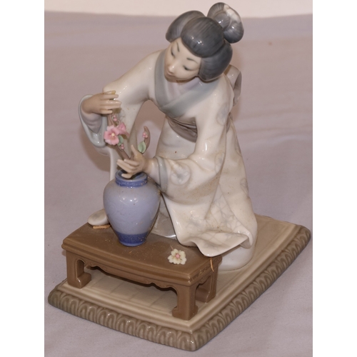 81 - A Lladro figure of a kneeling lady arranging flowers, 19cm high