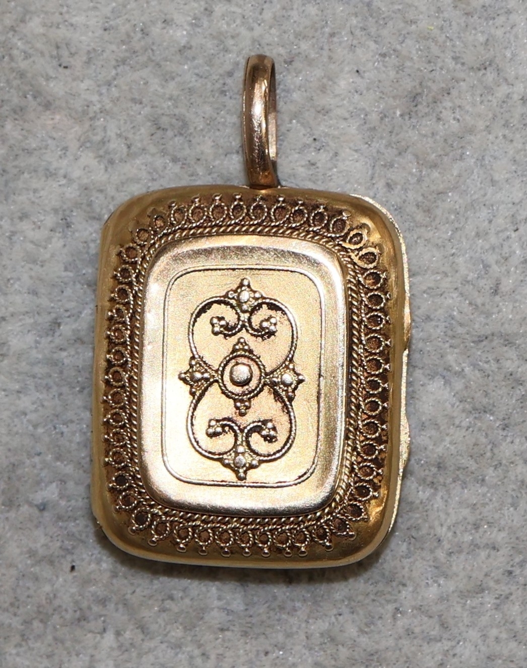 A 9ct gold rectangular shaped locket with raise scroll decoration, 9 grams
