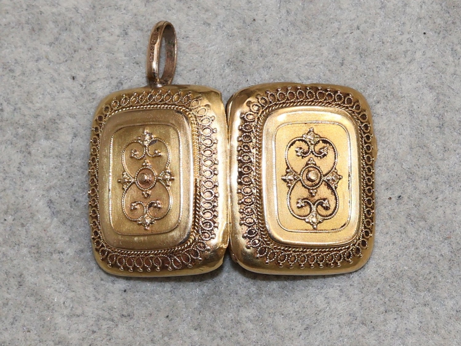 A 9ct gold rectangular shaped locket with raise scroll decoration, 9 grams