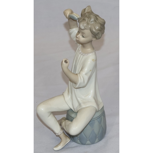 37 - A Lladro figure of a seated young girl brushing her hair (hand mirror missing), 21cm high