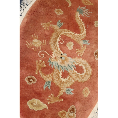 4067 - An oval Oriental rug on red ground with dragon to centre, 175cm x 116cm overall.