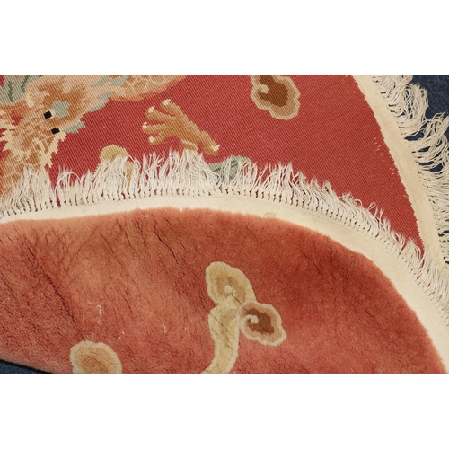 4067 - An oval Oriental rug on red ground with dragon to centre, 175cm x 116cm overall.