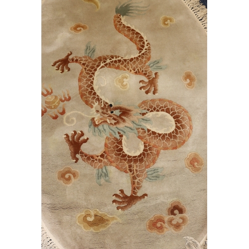 4068 - An oval Oriental rug on beige ground with dragon to centre, 175cm x 116cm overall.