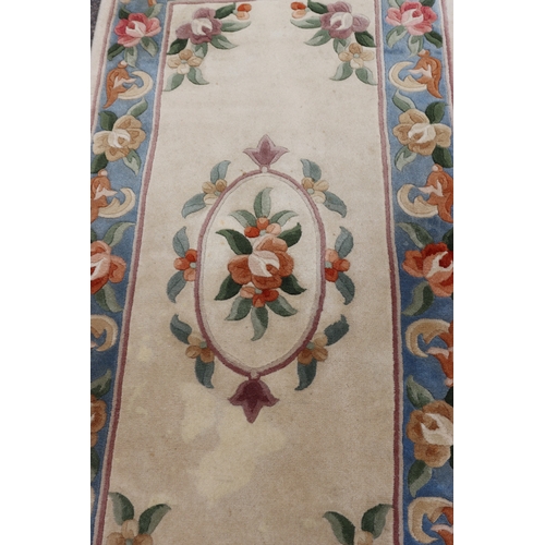 4075 - A small rug on cream ground with floral pattern, 176cm x 76cm (scattered spots and marks).