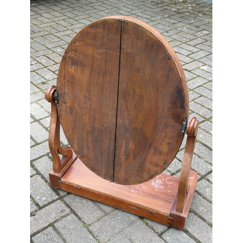 4093 - A 19th Century walnut oval swing toilet mirror with hinged top and on bun feet, 61.5cm wide, 28cm de... 