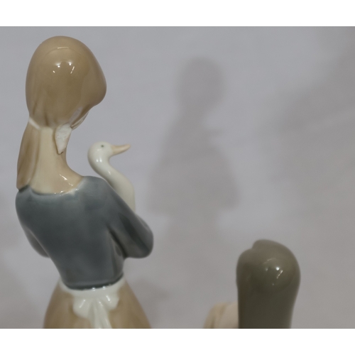 92 - A Lladro figure of a young girl holding a pig, 17.5cm high (1 hair plait missing) and a taller Nao f... 