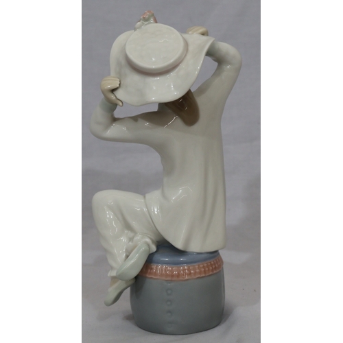 97 - A Lladro figure of a seated child on a pouffe wearing a hat, 20.cm high
