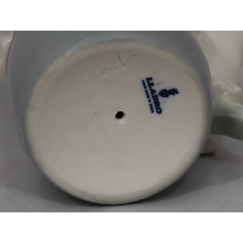 97 - A Lladro figure of a seated child on a pouffe wearing a hat, 20.cm high