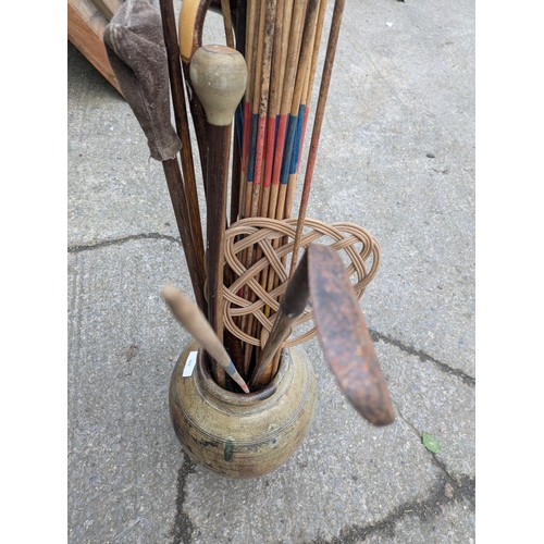 869 - A Large Aged Clay Pot With Walking Sticks, Golf Clubs, Etc