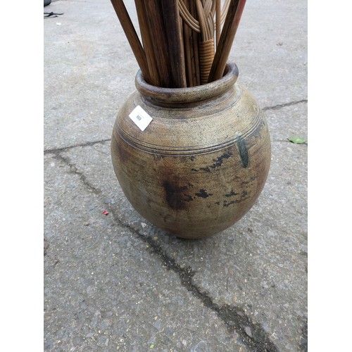 869 - A Large Aged Clay Pot With Walking Sticks, Golf Clubs, Etc