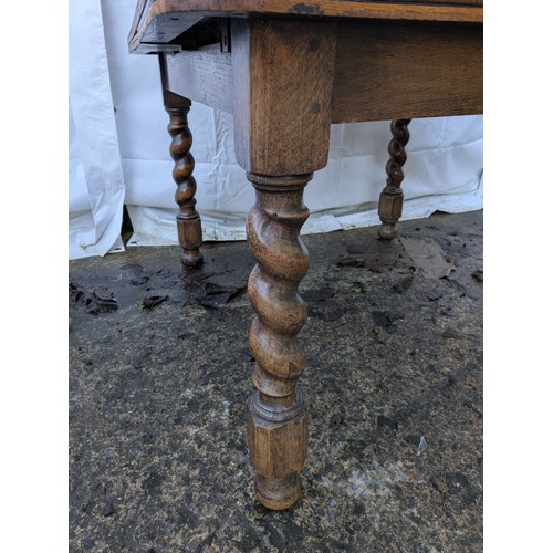 462 - An antique oak draw leaf extending dining table with crank extension handle and barley twist legs