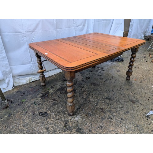 462 - An antique oak draw leaf extending dining table with crank extension handle and barley twist legs