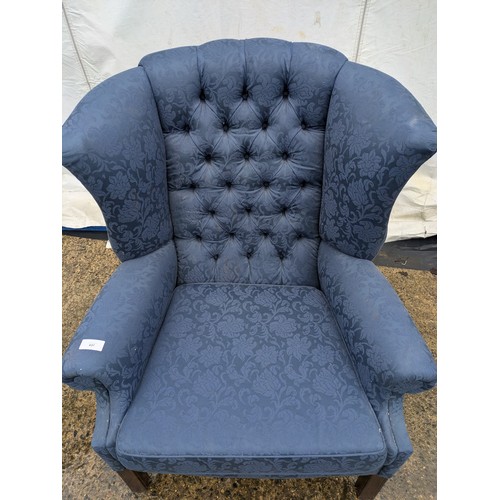 437 - A vintage wing back armchair in blue floral upholster and buttoned back