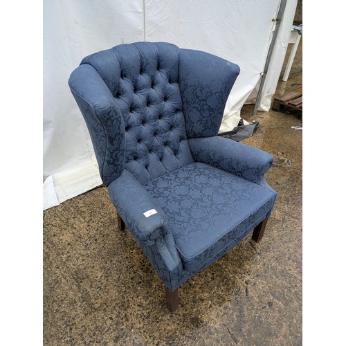 437 - A vintage wing back armchair in blue floral upholster and buttoned back