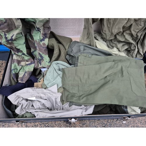 522 - A large blue canvas storage trunk with a large quantity of military clothing including trousers, jum... 