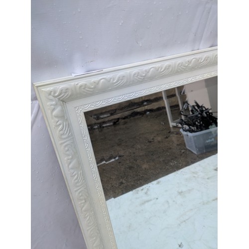 415 - An ornate bevelled edge mirror with an intricately designed white frame