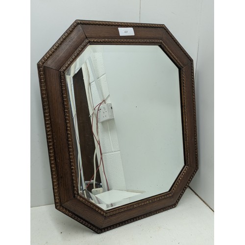 437 - A vintage bevelled edge mirror in an octagonal oak frame