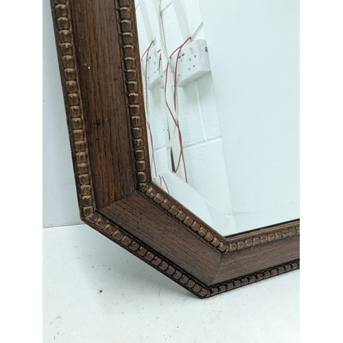 437 - A vintage bevelled edge mirror in an octagonal oak frame