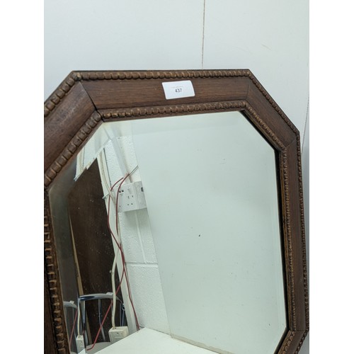 437 - A vintage bevelled edge mirror in an octagonal oak frame