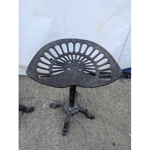 602 - A pair of rustic wrought iron stools in the style of tractor seats.