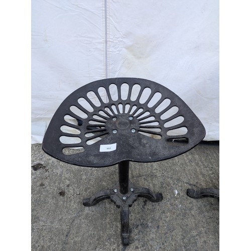 602 - A pair of rustic wrought iron stools in the style of tractor seats.