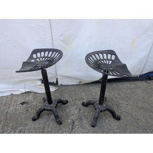 602 - A pair of rustic wrought iron stools in the style of tractor seats.